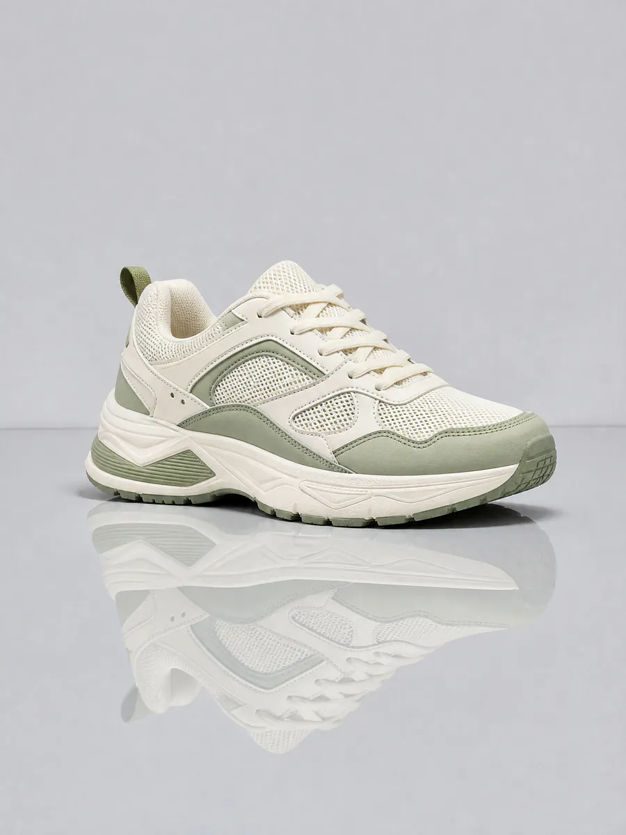 Product photo of a cream and sage running shoe split into two layers: the studio backdrop and the shoe